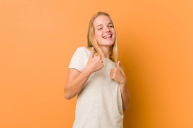 Sevimli ve doğal genç kadın, gülümseyerek ve kendinden emin her iki başparmak yükselterek.