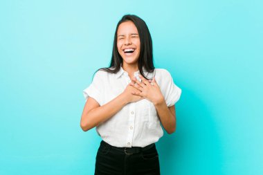 Mavi bir duvarın karşısında elini yüreğine koyan, mutlu genç İspanyol bir kadın..