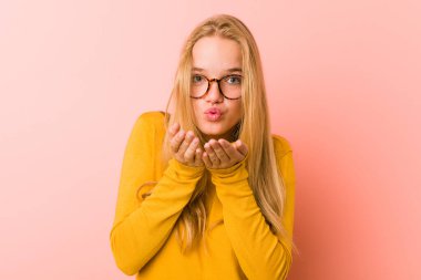 Dudaklarını kıvıran ve hava öpücüğü vermek için avuçlarını tutan sevimli genç bir kadın..