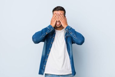 Genç yakışıklı Filipino adam eller ile gözleri kapsar, geniş bir sürpriz bekliyor gülümsüyor.