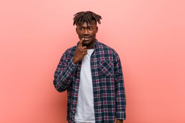 Genç Afrikalı siyahi adam şüpheli ve şüpheci bir ifadeyle yana bakıyor..