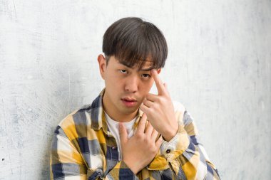 Genç Çinli adam parmak hareketiyle hayal kırıklığı yaratıyor.