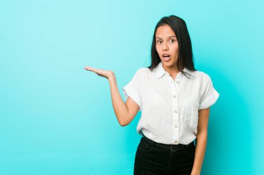 Mavi duvara yaslanmış genç, Latin asıllı havalı bir kadın, avuç içinin fotokopisini çekmekten etkilenmiş..