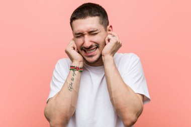 Kulaklarını elleriyle kapatan sıradan bir genç..