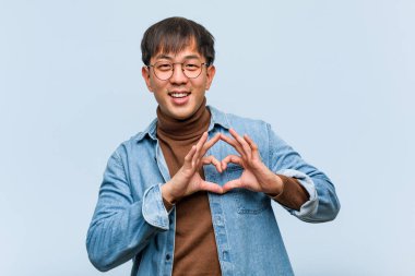 Genç Çinli adam elleri ile kalp şekli yapıyor