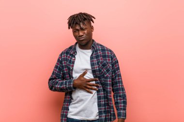 Genç Afrikalı siyahi adam karnına dokunuyor, nazikçe gülümsüyor, yemek yiyor ve tatmin oluyor..