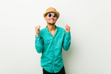 Yaz kıyafetleri giymiş, yumruğunu kaldıran mutlu ve başarılı genç bir İspanyol. Zafer konsepti.