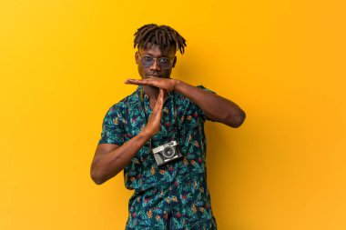 Tatil giymiş genç siyah Rasta adam bir mola jesti gösteriyor.