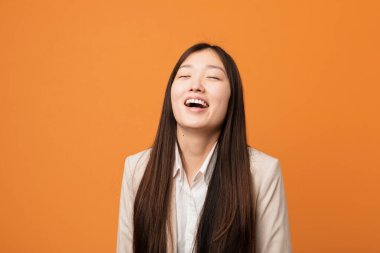 Genç Çinli kadın gevşemiş ve mutlu bir şekilde gülüyor, boynunda dişlerini gösteriyor..