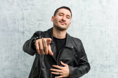 Genç rockçı başparmağıyla işaret ediyor, gülüyor ve kaygısız.