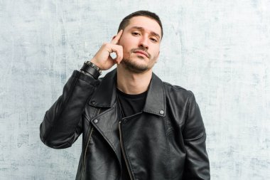 Genç bir rockçı şakağı parmağıyla işaret ediyor, düşünüyor, bir göreve odaklanıyor..