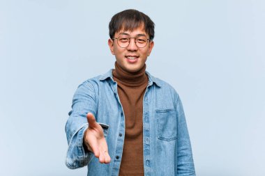 Genç Çinli adam birini selamlamak için uzanıyor.