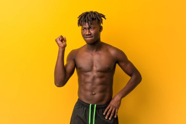 Genç siyah adam mayo giyiyor, kafasının arkasına dokunuyor, düşünüyor ve bir seçim yapıyor..