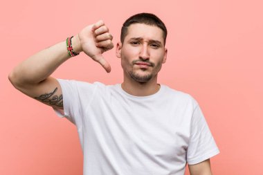 Genç, sıradan bir adam hoşlanmadığı bir jest yapıyor, başparmakları aşağıda. Anlaşmazlık konsepti.