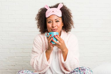 Genç afro-amerikan kadın yatakta bir fincan tutan