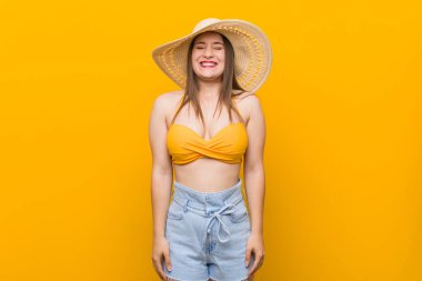 Hasır şapka takan genç beyaz kadın, yaz bakışı, gülüyor ve gözlerini kapatıyor, rahatlamış ve mutlu hissediyor..