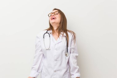 Genç bir doktor kadın beyaz bir duvara yaslanmış gevşemiş ve mutlu bir şekilde gülüyor, boynunda diş izleri var..