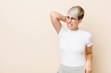 Genç, otantik, beyaz tişörtlü bir kadın başının arkasına dokunuyor, düşünüyor ve bir seçim yapıyor..