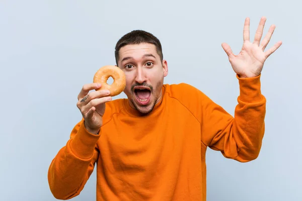 Joven Caucásico Sosteniendo Donut Celebrando Una Victoria Éxito — Foto de Stock