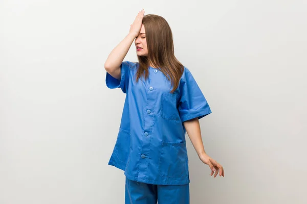 Jovem Enfermeira Mulher Contra Uma Parede Branca Esquecendo Algo Batendo — Fotografia de Stock