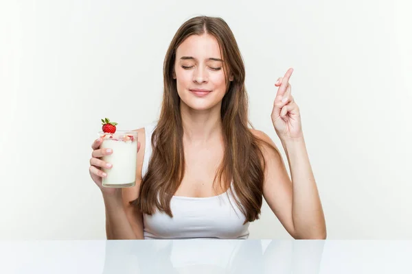 Young Caucasian Woman Holding Smoothie Crossing Fingers Having Luck — Stock Photo, Image