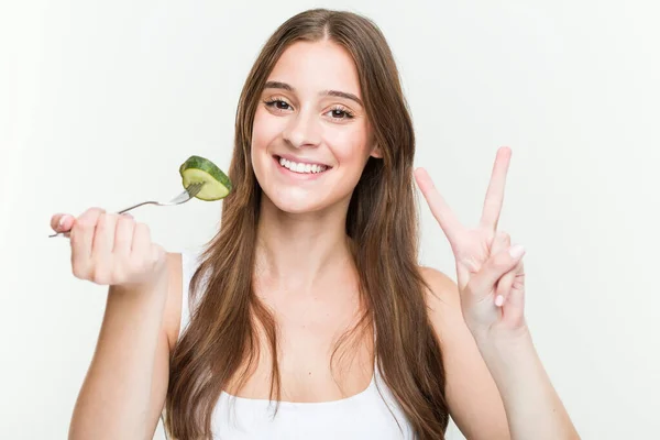 Junge Kaukasierin Isst Gurke Und Zeigt Nummer Zwei Mit Fingern — Stockfoto