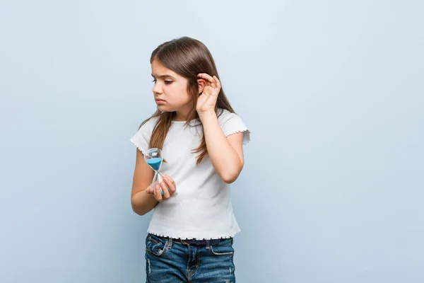 Mała Kaukaska Dziewczyna Trzymając Klepsydrę Próbuje Słuchać Plotki — Zdjęcie stockowe