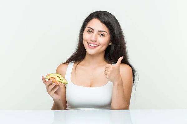 Young Hispanic Woman Holding Avocado Toast Smiling Raising Thumb — Stock Photo, Image