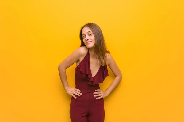 Young natural woman wearing a red dress against an orange wall — Stock Photo, Image