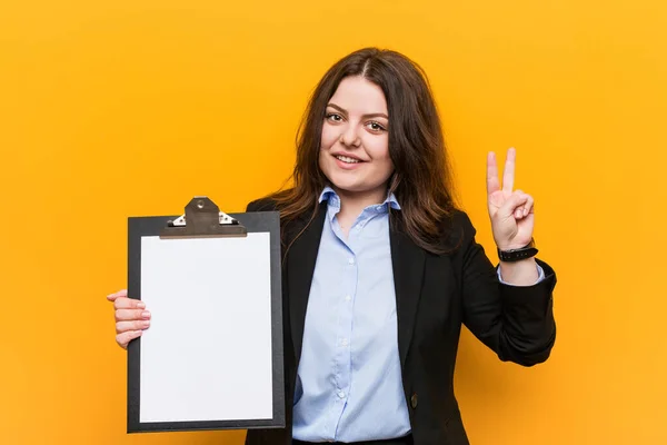 Młody Krzywizna Rozmiar Biznes Kobieta Trzymając Schowek Pokazując Znak Zwycięstwa — Zdjęcie stockowe