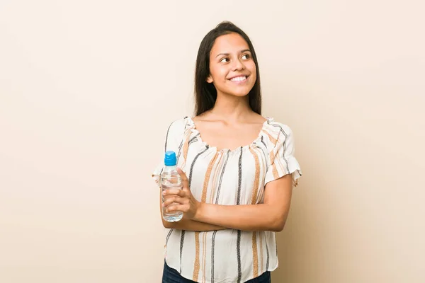 Junge Hispanische Frau Hält Eine Flasche Wasser Und Lächelt Selbstbewusst — Stockfoto