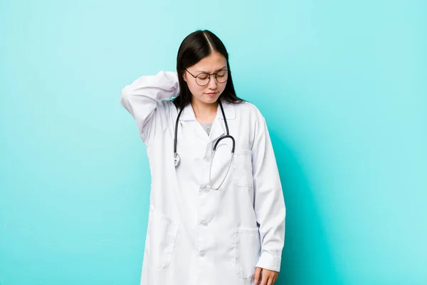 Young chinese doctor woman suffering neck pain due to sedentary lifestyle.