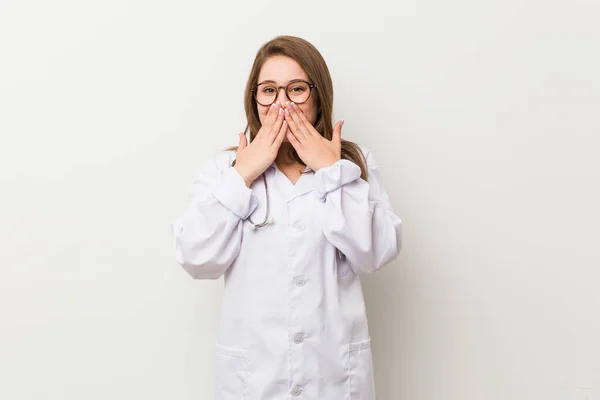 Jonge Dokter Vrouw Tegen Een Witte Muur Lachen Iets Bedekken — Stockfoto