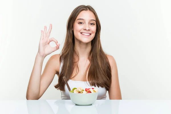 Jonge Kaukasische Vrouw Eten Fruit Kom Vrolijk Zelfverzekerd Tonen Gebaar — Stockfoto