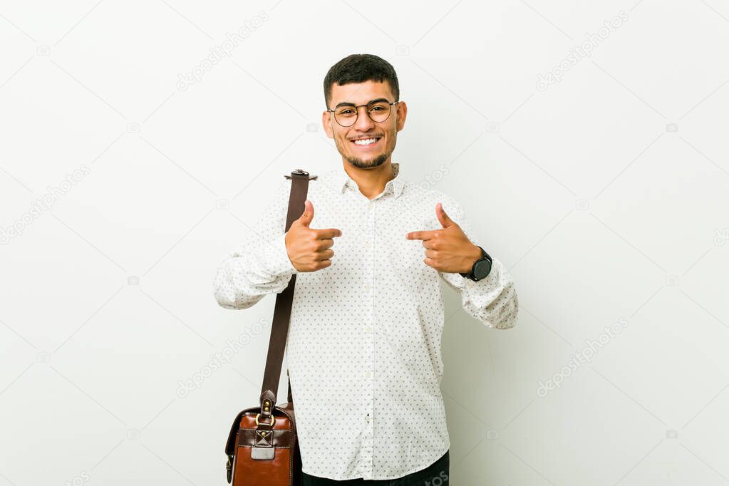 Young hispanic casual business man surprised pointing with finger, smiling broadly.