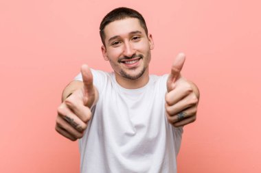 Başparmakları havada genç bir adam, bir şey için tezahürat yapıyor, destek ve saygı kavramı..