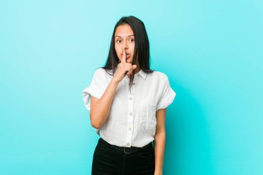 Mavi duvara yaslanmış, sır saklayan ya da sessizlik isteyen İspanyol asıllı genç bir kadın..