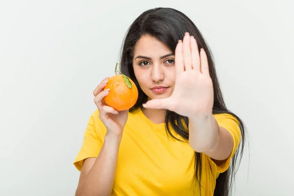 Giovane Donna Ispanica Possesso Arancione Piedi Con Mano Tesa Mostrando — Foto Stock