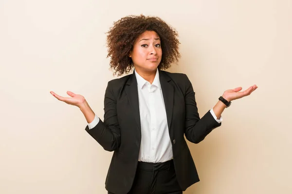 Young business african american woman doubting and shrugging shoulders in questioning gesture.