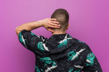 Tatil kıyafeti giyen genç adam arkasını dönüp bir şeyler düşünüyor..