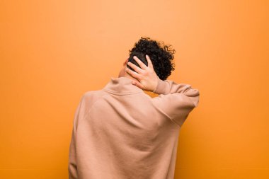 Kahverengi arka planda gülümseyen, kendine güvenen, elleriyle çenesine dokunan Afrikalı genç bir Amerikalı kadın..