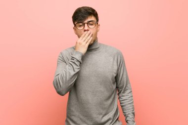 Genç, zeki bir öğrenci, esniyor. Ağzı eliyle kapatan yorgun bir jest yapıyor..