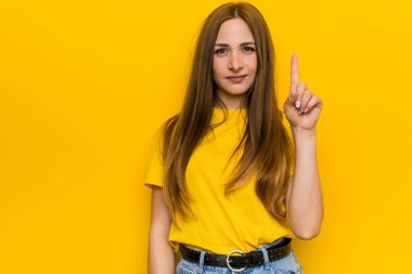 Kızıl saçlı genç kadın bir numarayı parmaklarıyla gösteriyor..