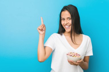 Genç İspanyol kadın elinde şeker kasesi tutarken neşeli bir şekilde işaret parmağıyla işaret ediyor..