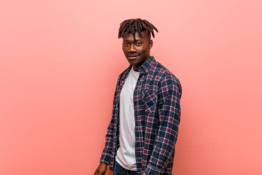 Genç Afrikalı siyah adam gülümseyen, neşeli ve hoş bir şekilde yana bakıyor..