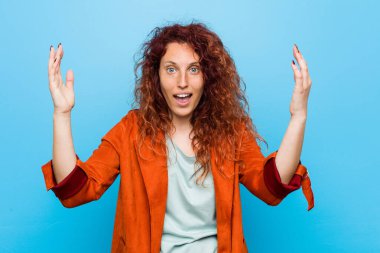 Genç kızıl saçlı zarif kadın hoş bir sürpriz yapıyor. Heyecanlı ve el kaldırıyor..