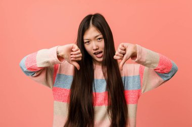 Genç havalı Çinli kadın baş parmağını aşağı gösteriyor ve hoşlanmadığını ifade ediyor..