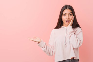 Spor kıyafeti giyen genç, güzel bir Arap kadın avucunun içinde fotokopi alanı tutuyor, el üstünde tutuyor. Şaşırmış ve mutlu..