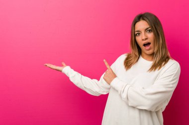 Bir duvara karşı genç otantik karizmatik gerçek insanlar kadın avuç üzerinde bir kopya alanı tutarak heyecanlı.