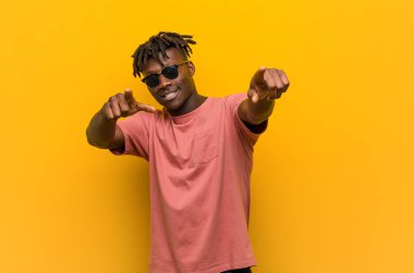 Gündelik siyah gözlüklü genç adam öne doğru gülümsüyor..